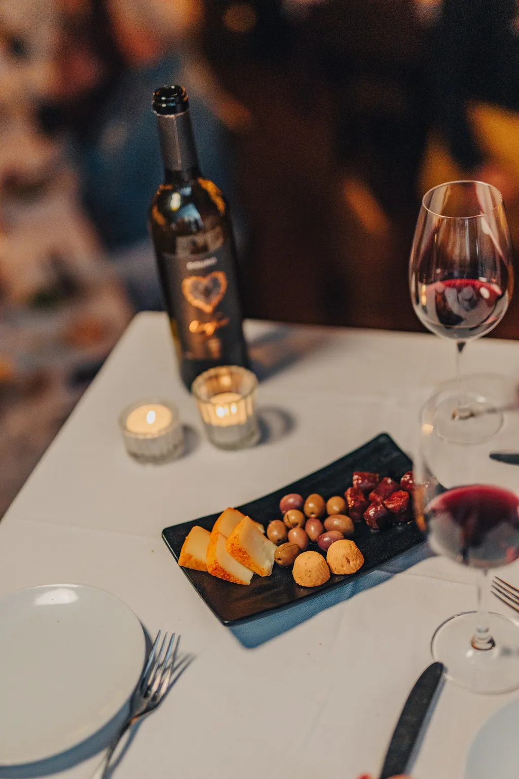 A mesa posta com o couvert, o vinho e a luz das velas