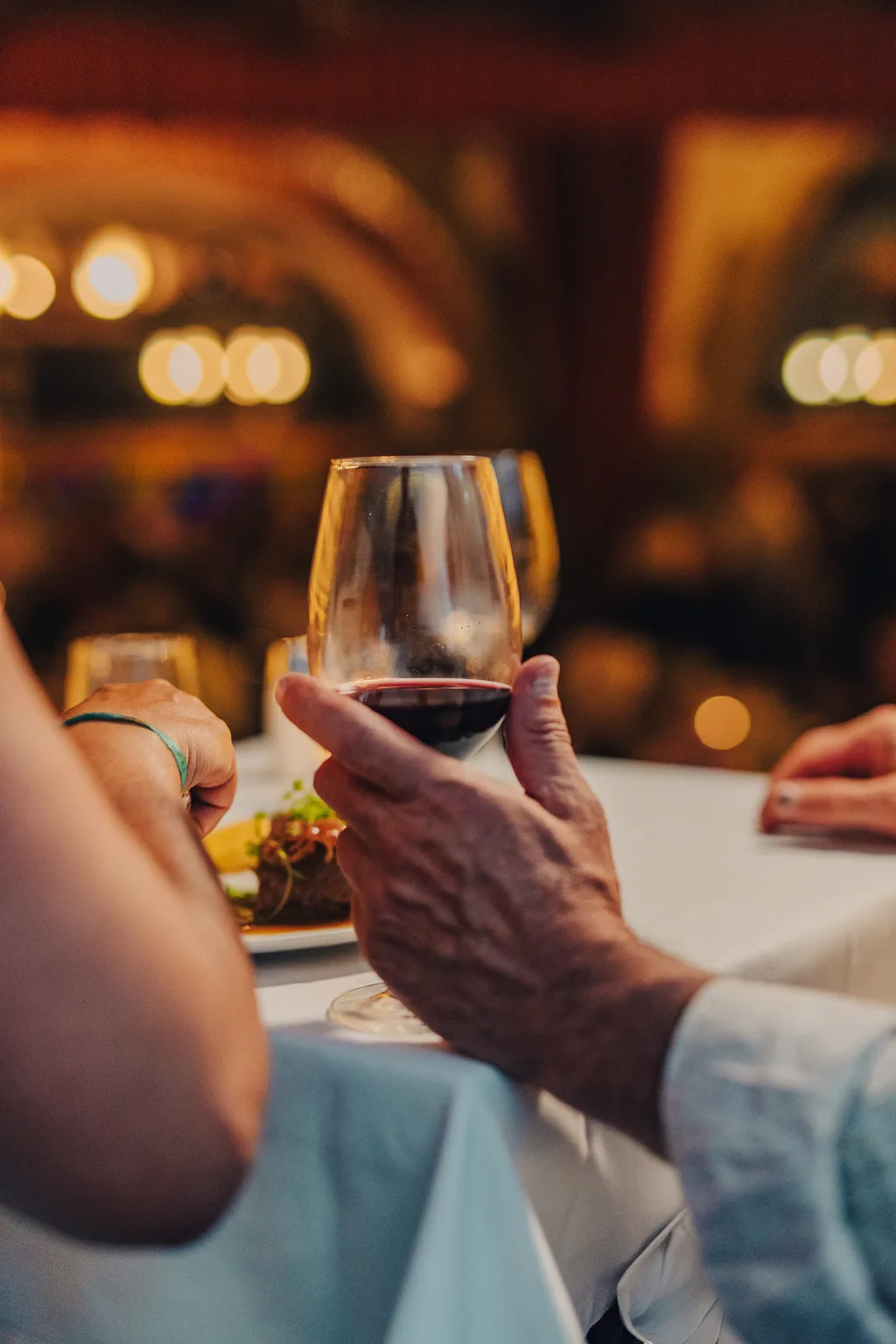 Um copo de tinto na mão, a sala acesa por trás