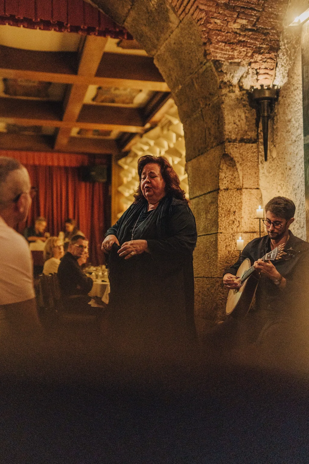 Fadista a cantar entre as mesas, com o guitarrista ao lado