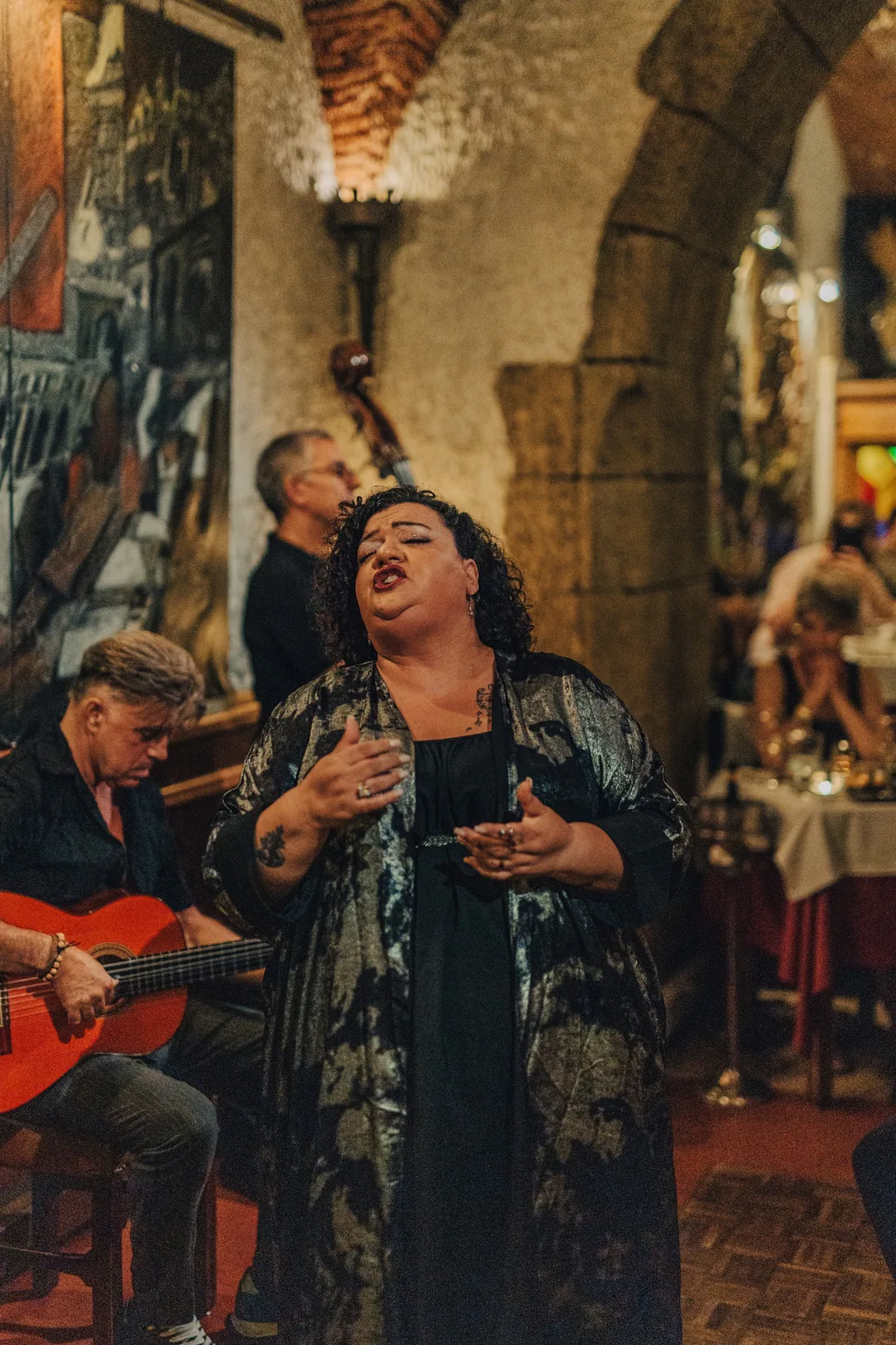 Fadista de xaile a cantar de olhos fechados, junto ao guitarrista